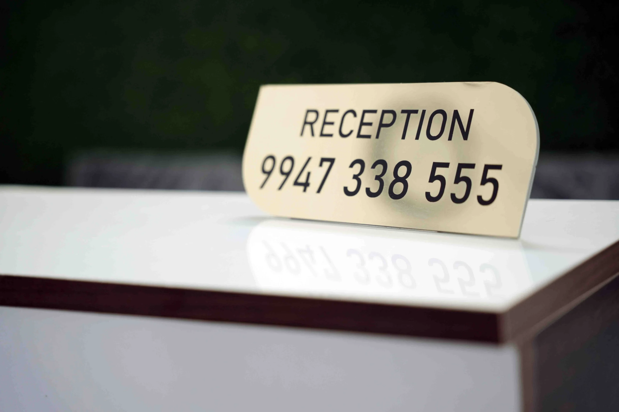 Reception contact sign at Gold Suite Kakkanad displaying hotel phone number for booking and guest assistance.