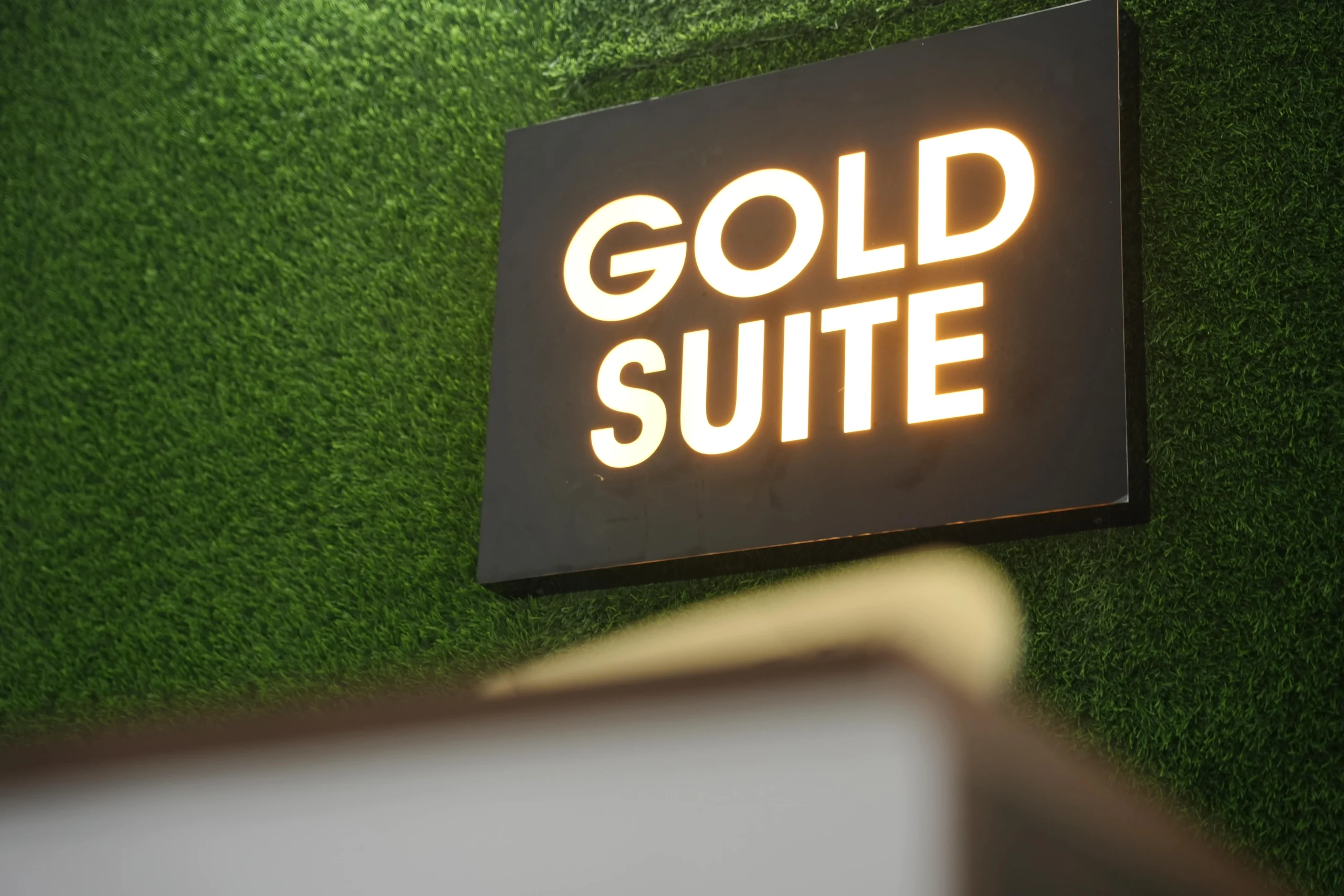 Illuminated Gold Suite hotel reception sign on green grass wall at Kakkanad, Kochi.