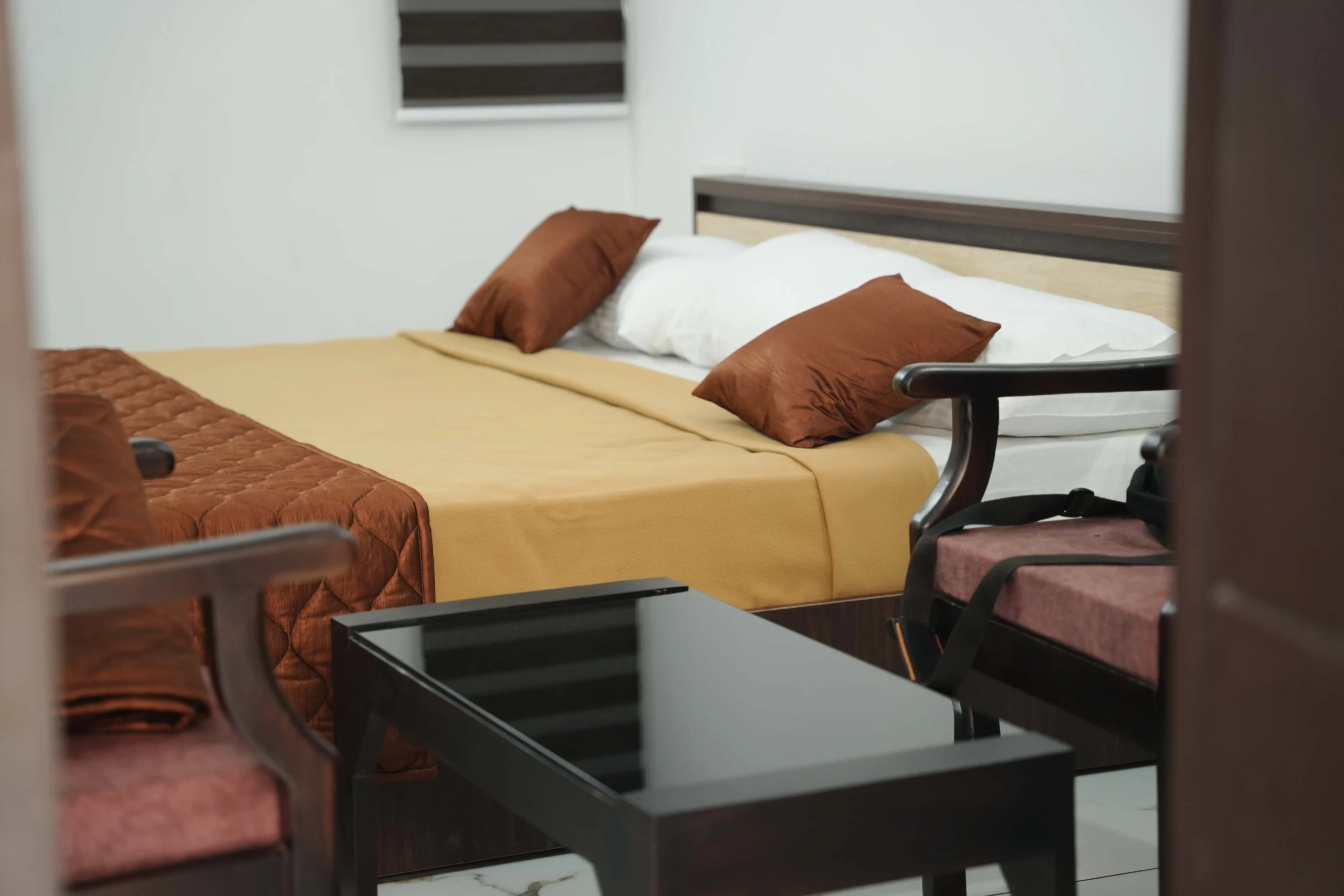 Comfortable twin bed Best Hotels in Kakkanad Kochi white bedding, brown bed runners, soft lighting and modern interiors at Gold Suite in Kakkanad, Kochi.